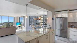 A modern kitchen with a large island, stainless steel appliances, and a view of a library.