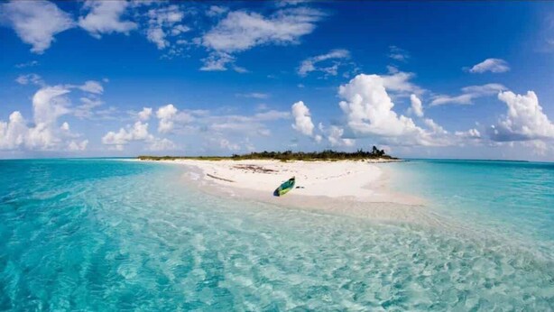 A beach with clear turquoise waters and a sandy shore.