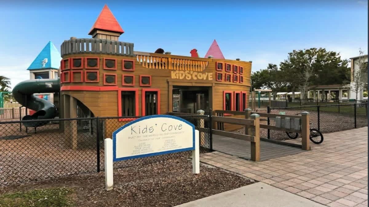 Een kinderspeelplaats genaamd Kids' Cove, met een speeltoestel en een bordje.