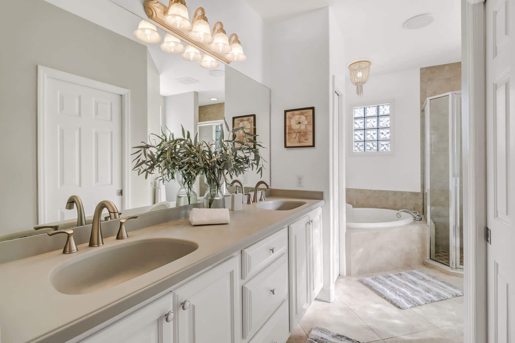 A bathroom with two sinks, a large mirror, a shower, and a window.
