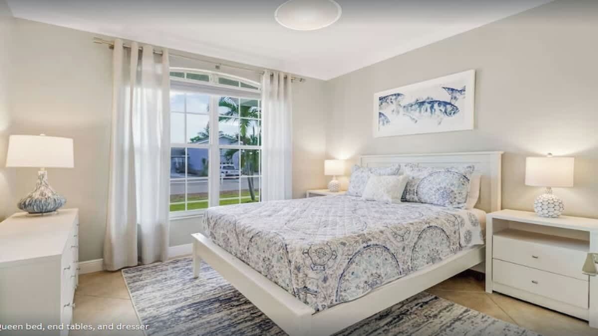 A bedroom with a queen bed, end tables, and a dresser.