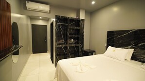 Una habitación de hotel moderna con cabecera de mármol, un espejo grande, un armario con detalles de mármol y una cama bien hecha.