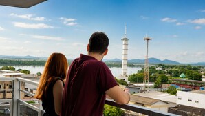 Una pareja observa un paisaje urbano con una torre destacada y una masa de agua.