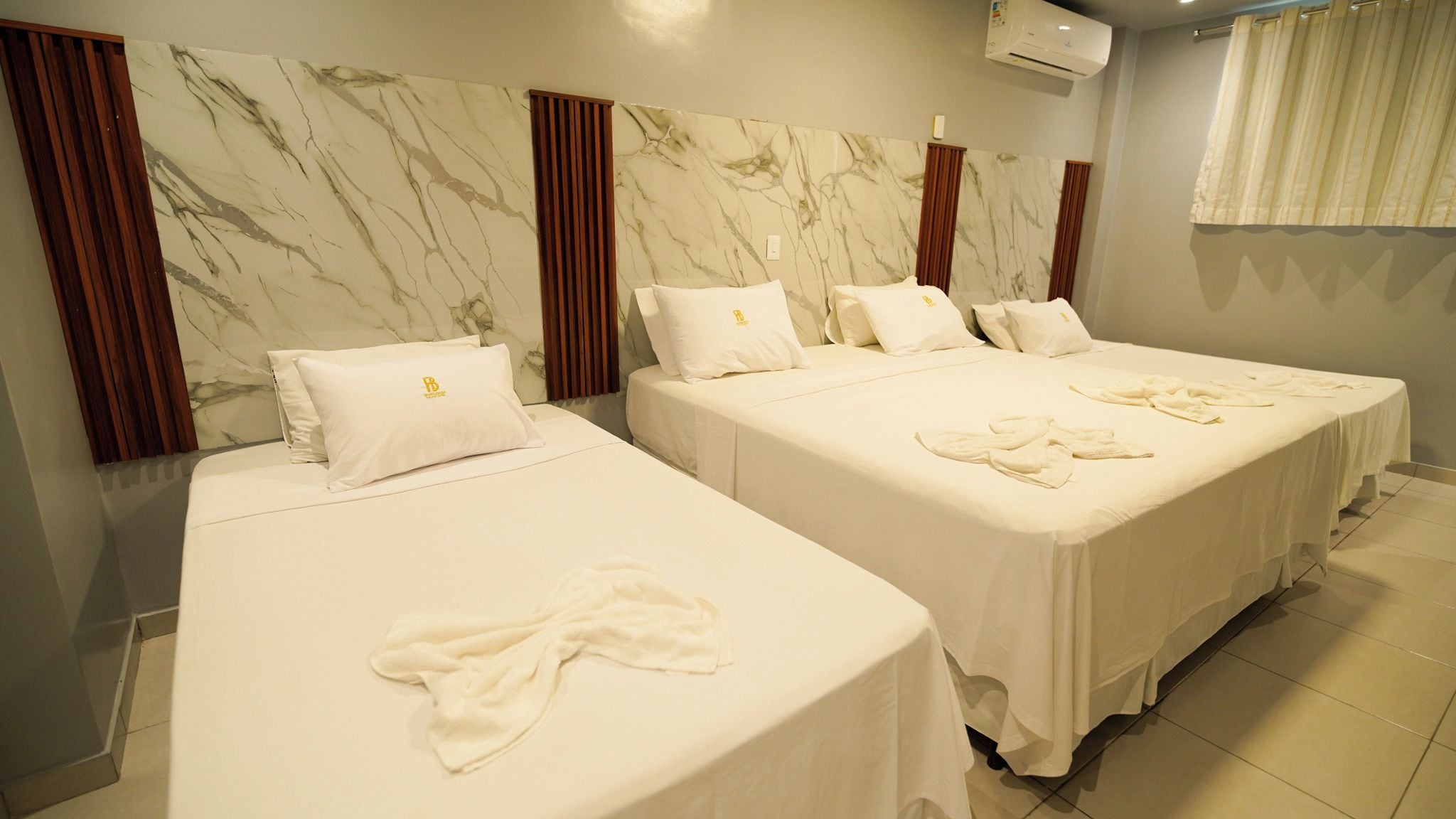 A hotel room with two beds, marble-patterned walls, and a bathroom with a shower curtain.