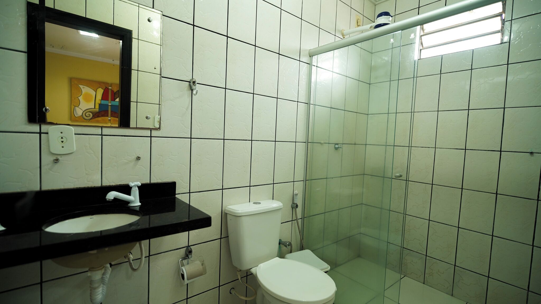 Baño con lavabo negro, inodoro blanco y cabina de ducha de cristal.