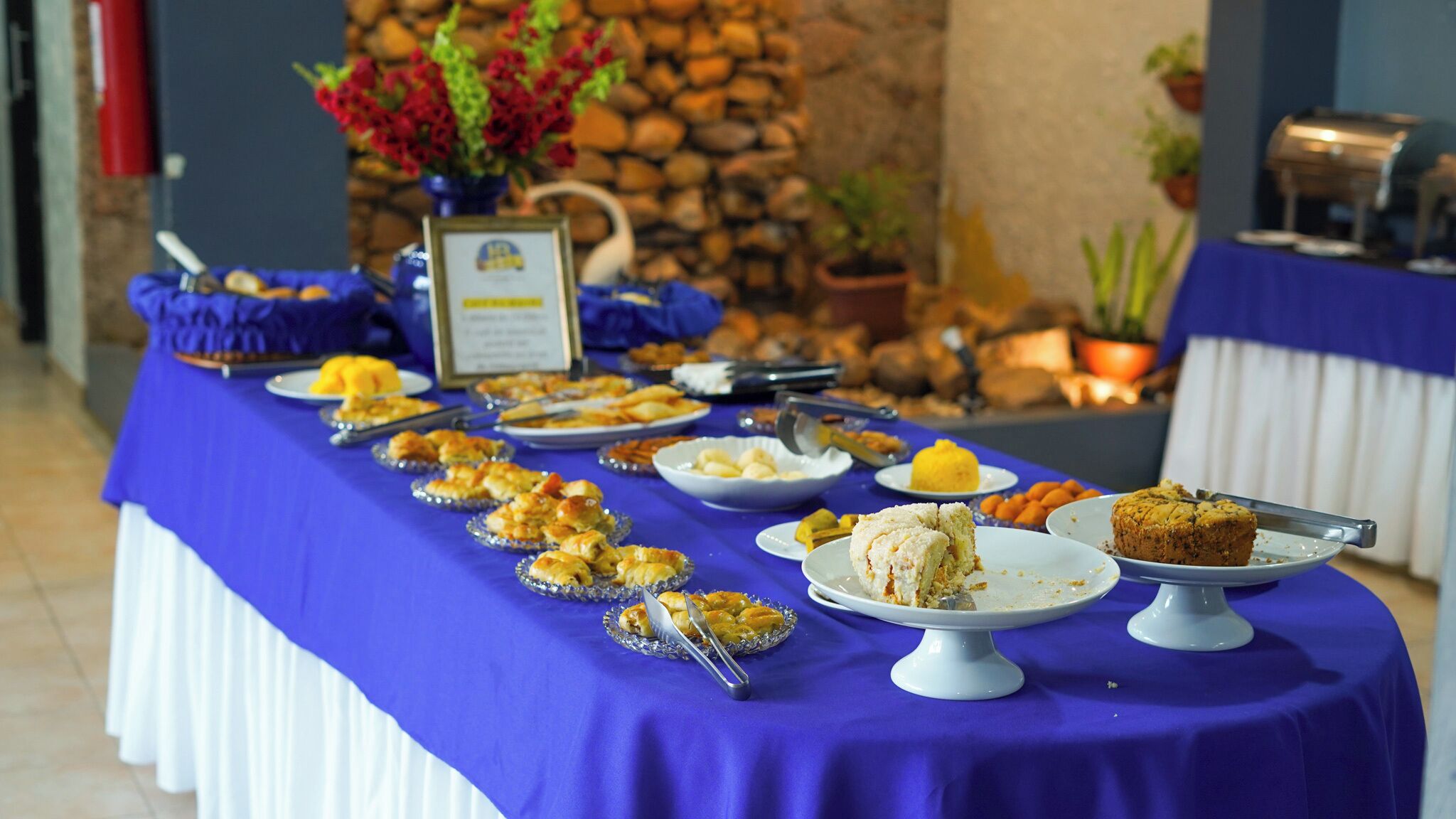 A buffet table with various dishes, a stone wall, and potted plants in the background.