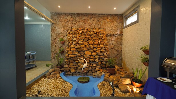Un muro de piedra con una fuente, plantas en macetas y una zona de barbacoa.