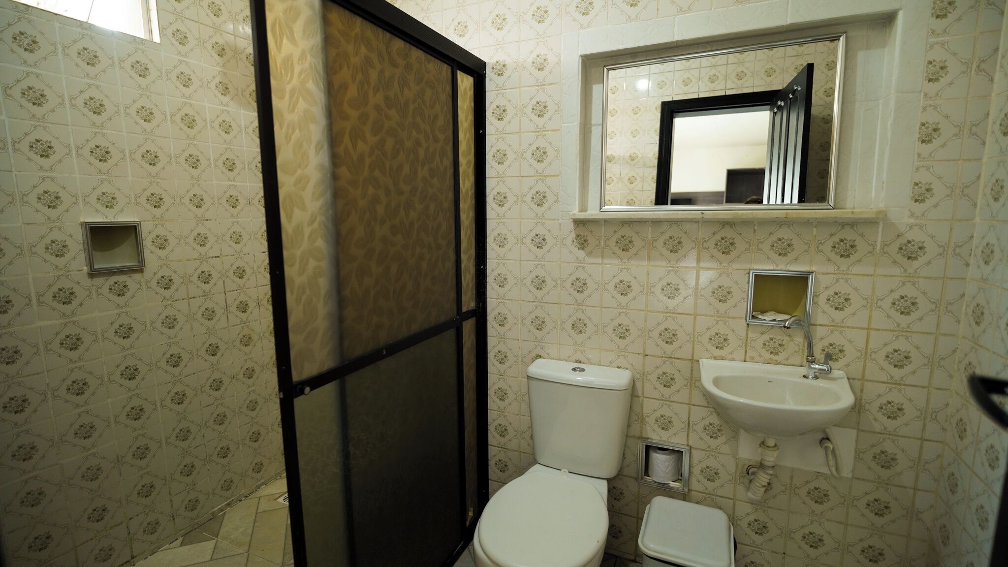 A bathroom with a toilet, sink, and mirror.