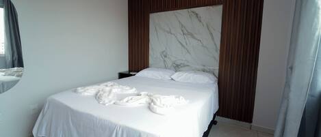 A modern bedroom with a large bed, a marble headboard, and a view of the city.