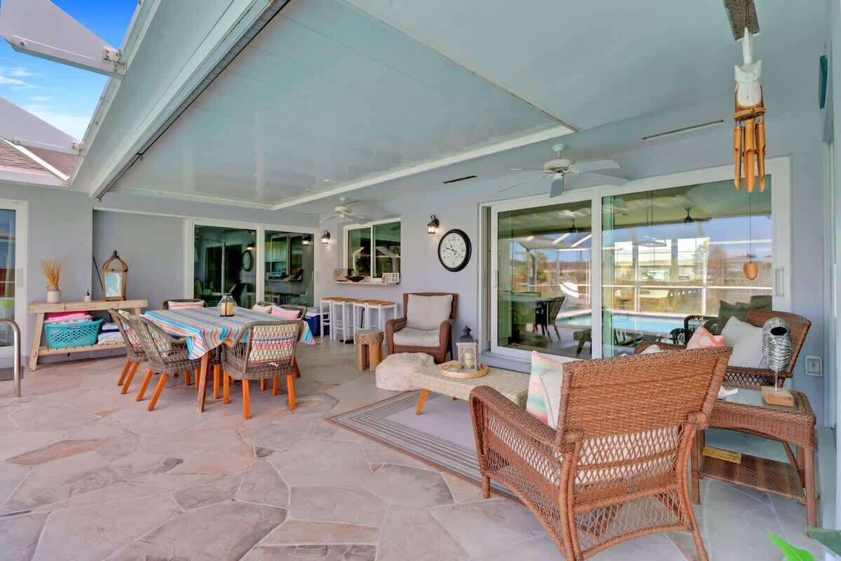 A covered patio area with a dining table, wicker chairs, and a sofa.