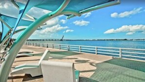 A waterfront promenade with seating areas and a railing overlooking the water.