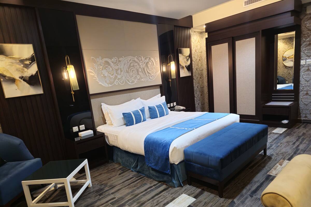 Habitación de hotel moderna con una cama grande, una mesita de noche, una silla y una pequeña mesa.