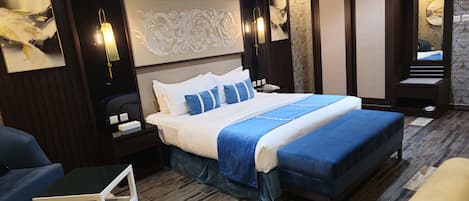 A modern hotel room with a large bed, a bedside table, a chair, and a small table.