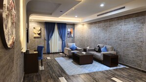 A modern living room with a sofa set, a coffee table, and a TV. - Royal Boutique Hotel (Khamis Mushait)