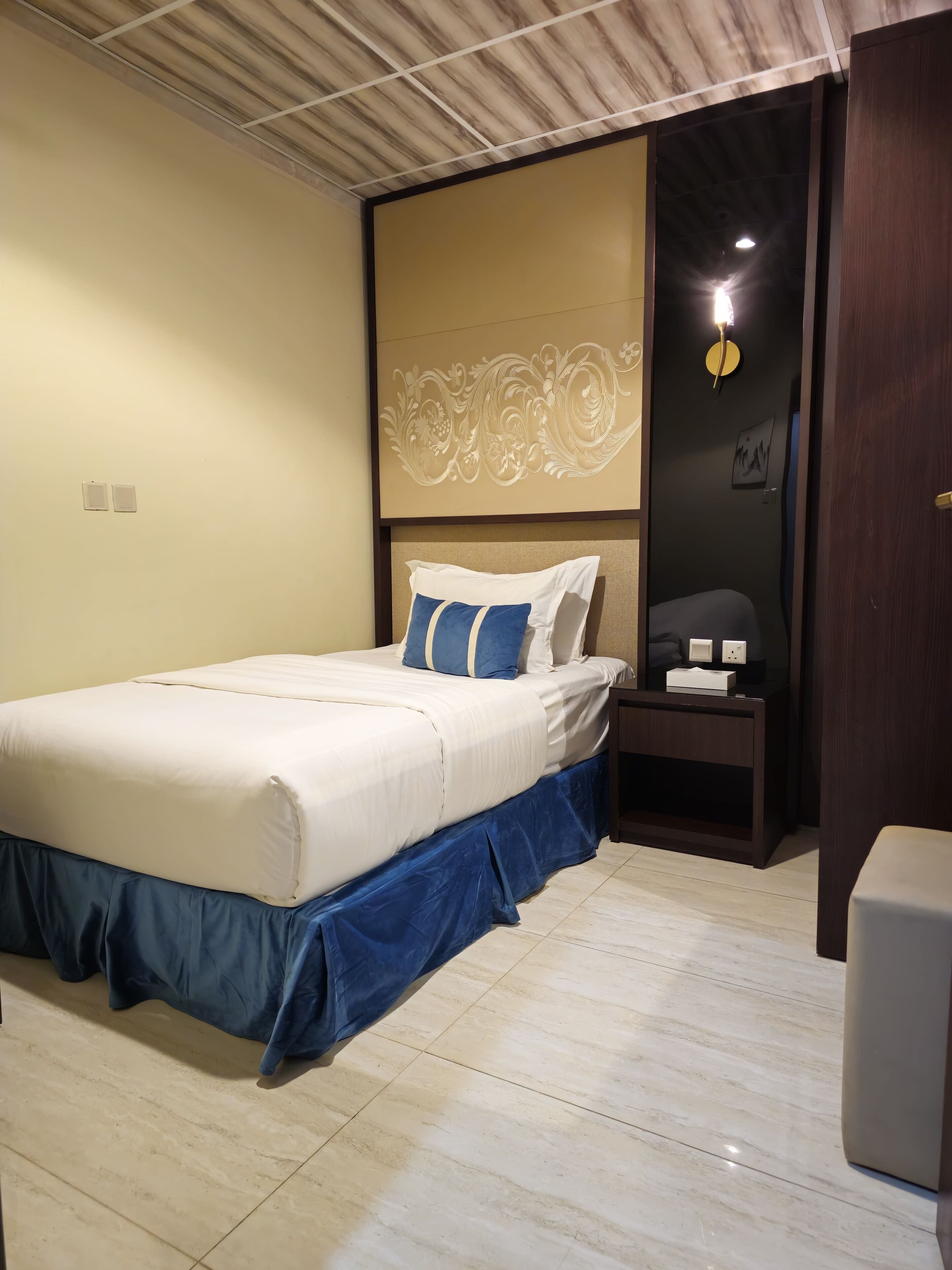 A neatly arranged bedroom with a bed, a nightstand, and a wall-mounted light fixture.