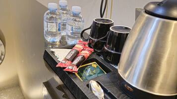 A minibar with bottled water, coffee mugs, a coffee pot, and a spoon.