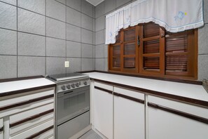 Une cuisine équipée d’un four encastré, d’une cuisinière et d’une fenêtre avec des volets en bois.
