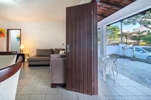 Un salon moderne avec un canapé, une cloison en bois et une vue sur la rue.