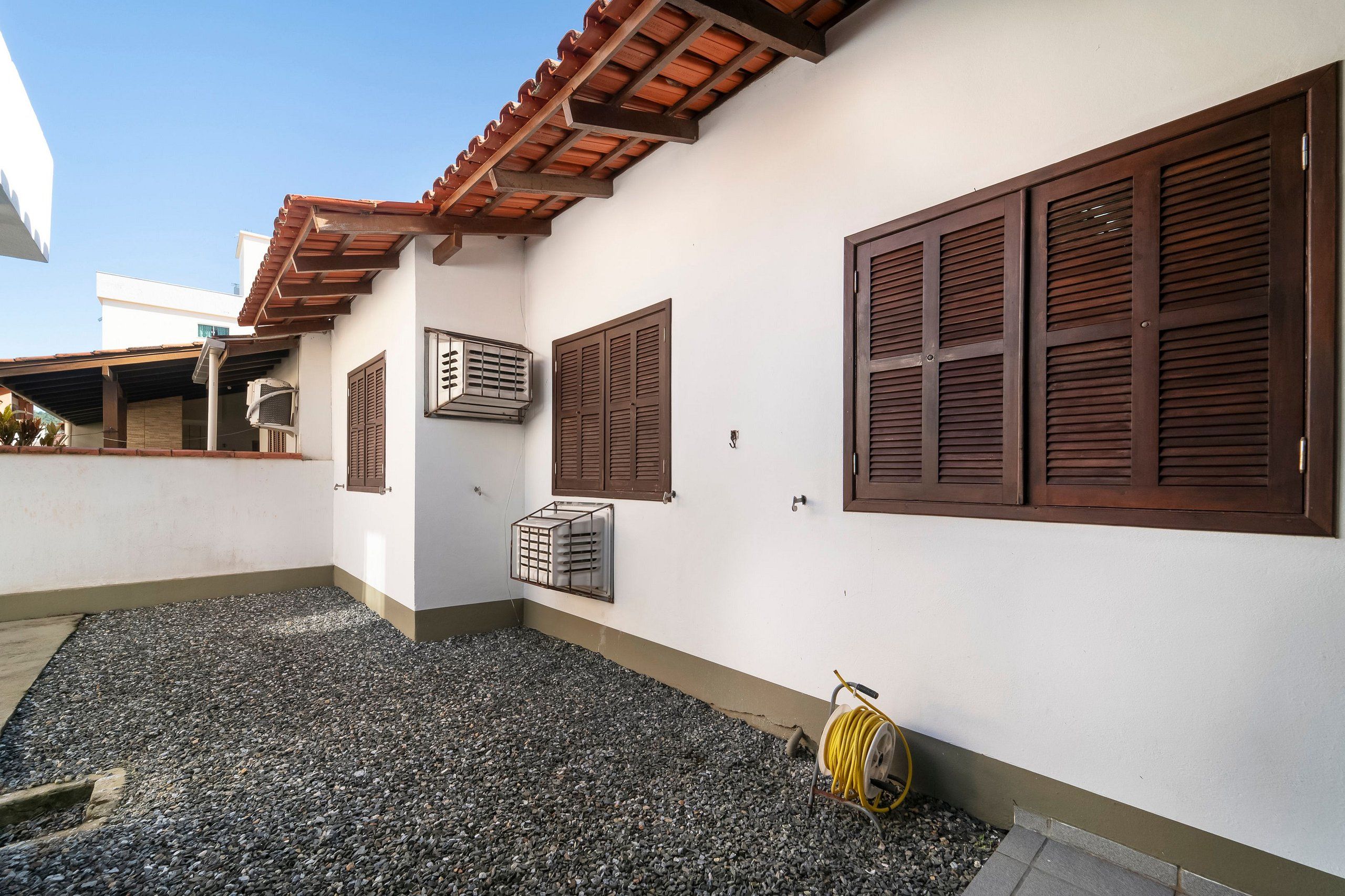 Um edifício com telhado telhado, venezianas de madeira e um aparelho de ar condicionado.