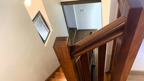 Een houten trap met een leuning en een ingelijste foto aan de muur.