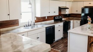 Una cocina moderna con armarios blancos, una estufa negra y un refrigerador de acero inoxidable.