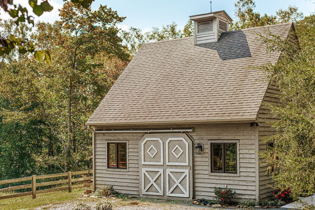 Une maison en bois à l’aspect rustique, avec un toit en pente, une cheminée et une cour clôturée.