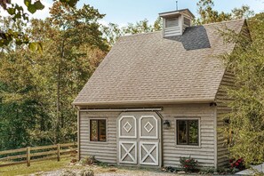 Ein rustikales Holzhaus mit einem geneigten Dach, einem Schornstein und einem umzäunten Garten.
