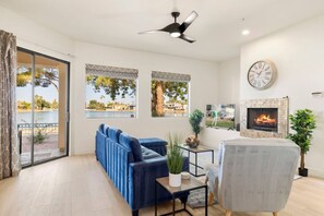 A modern living room with a blue sofa, a grey armchair, a fireplace, and a TV. - Lakefront Condo w/ Heated Pool + spa in Scottsdale (Scottsdale)