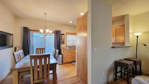 A dining area with a wooden table and chairs, a chandelier, and a view of the backyard through a window with curtains. - 2-story, 3 bedroom modern home with king and queen beds, living room and kitchen. (Ashland)