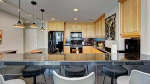 Una cocina moderna con una isla central, taburetes de bar e iluminación colgante.