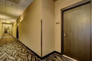 A hotel hallway with a patterned carpet, a door labeled '805', and a vertical light fixture on the wall.
