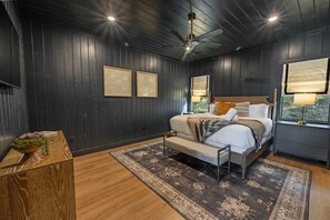 A bedroom with a bed, bedside tables, a window with a view, and a ceiling fan. - Favorite Luxury Cabin w stunning views 3 level Deck- sauna/Hot Tub/putting green (Broken Bow)