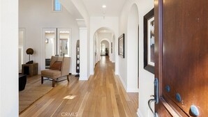 A spacious hallway with wooden flooring, a large wooden door, and a framed picture on the wall. - Pet Friendly Beautiful PGA West Spanish Style Home Private Oasis Beautiful Pool (La Quinta)