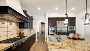 A modern kitchen with a central island, stainless steel appliances, and pendant lighting. - Pet Friendly Beautiful PGA West Spanish Style Home Private Oasis Beautiful Pool (La Quinta)