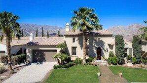 A two-story house with a tiled roof, a garage, and a well-maintained lawn. - Pet Friendly Beautiful PGA West Spanish Style Home Private Oasis Beautiful Pool (La Quinta)
