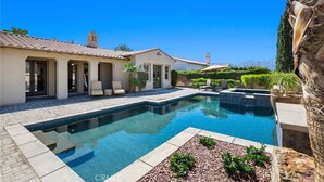 A swimming pool with a tiled deck, a covered patio with chairs, and a view of the ocean. - Pet Friendly Beautiful PGA West Spanish Style Home Private Oasis Beautiful Pool (La Quinta)