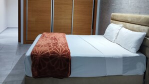 A modern bedroom with a bed, a wooden wardrobe, and a grey textured wall. - Les Belles Residences F (Tangier)