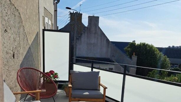 A balcony with a wooden table, two chairs, and a sofa.