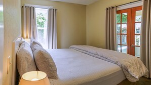 A bedroom with a bed, a lamp, and a window with curtains.