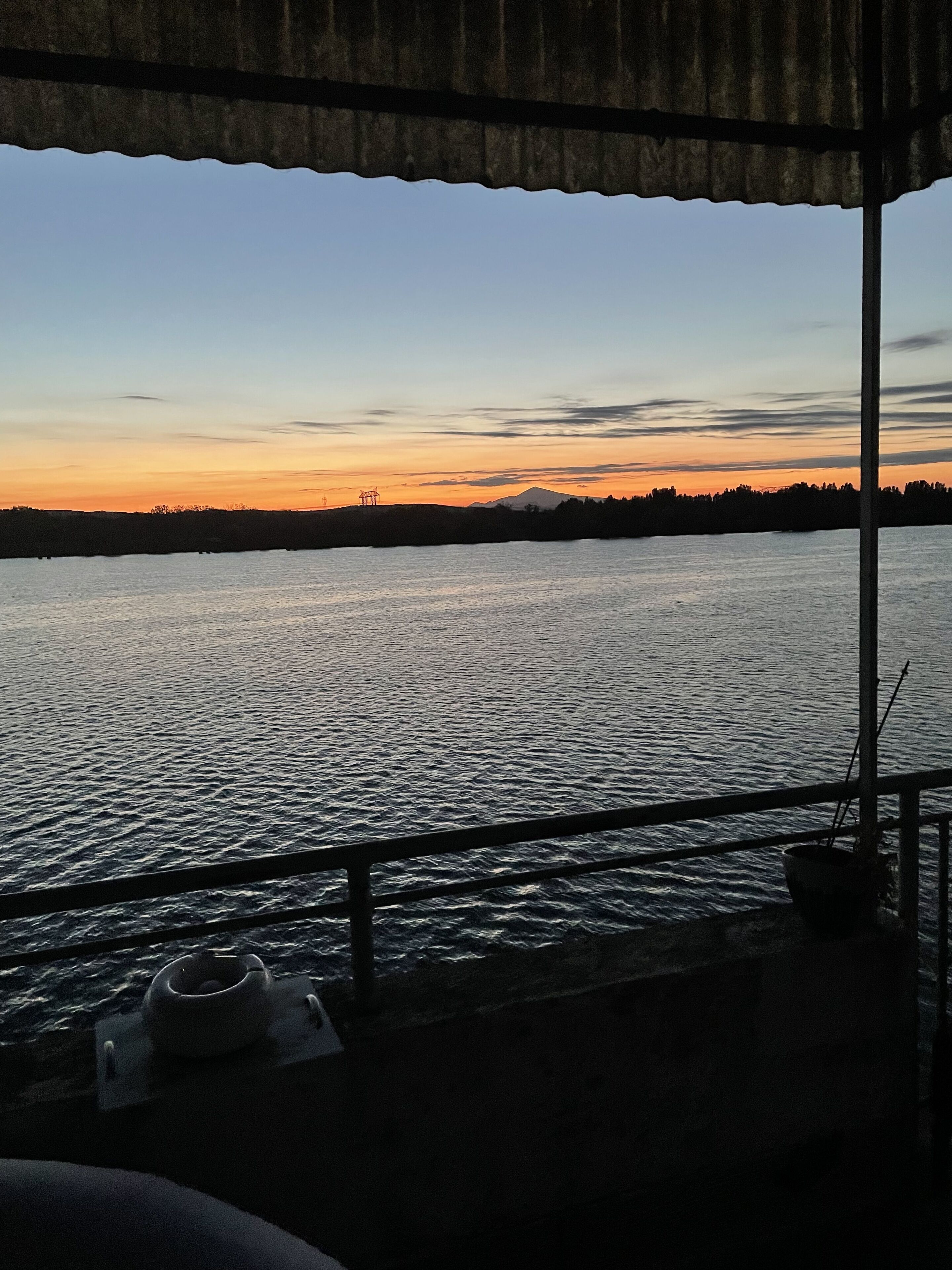 A view from a covered area overlooking a body of water with a distant mountain silhouette.