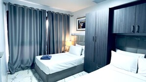 A hotel room with a bed, a wardrobe, a nightstand, and a lamp. - Bright and Airy Chalet Near the Beach (Al-Manasrah)