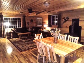 L’intérieur d’un chalet chaleureux, avec une table à manger en bois, des chaises et une cheminée.