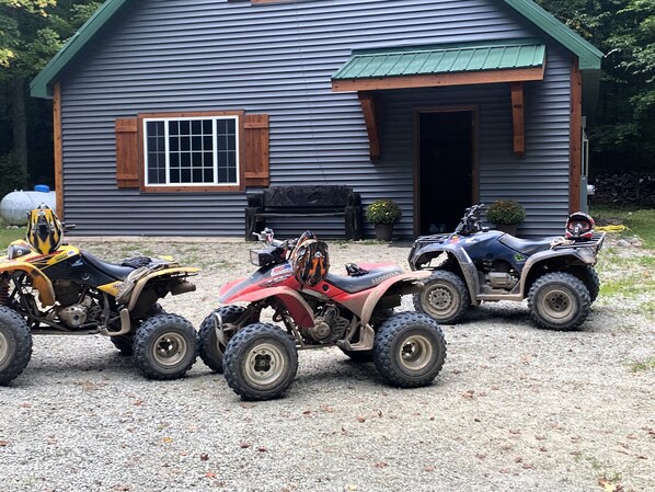Trois quads sont stationnés devant une maison dont l’allée est recouverte de gravier.