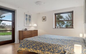 Une chambre à coucher avec un lit, une commode, une fenêtre donnant sur un beau paysage et une porte.