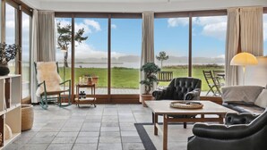 Une pièce spacieuse avec de grandes fenêtres, un coin salon confortable et une vue sur un lac.