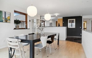 Une cuisine moderne avec un îlot central, des chaises blanches et des luminaires suspendus.