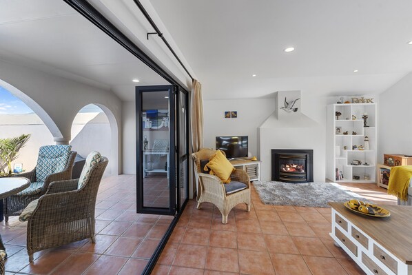A modern living room with a fireplace, wicker furniture, and a TV.