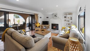 Ein modernes Wohnzimmer mit einer Sofagarnitur, einem Couchtisch, einem Fernseher und einem Kamin.