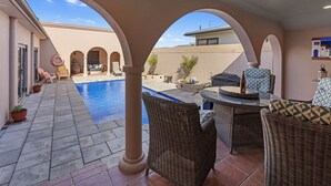 Eine Außenpatio-Terrasse mit Pool, Korbmöbeln und Blick auf das Gebäude im Hintergrund.