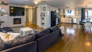 A modern living room with a dark gray sofa, a white coffee table, and a fireplace. - 4 units includes two cottages and two trailers with king and queen beds, kitchens, and dining areas. (Talent)